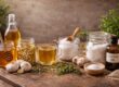 Natural home remedies displayed on a rustic wooden table including honey, garlic, herbal tea, apple cider vinegar, Epsom salt, baking soda, and castor oil